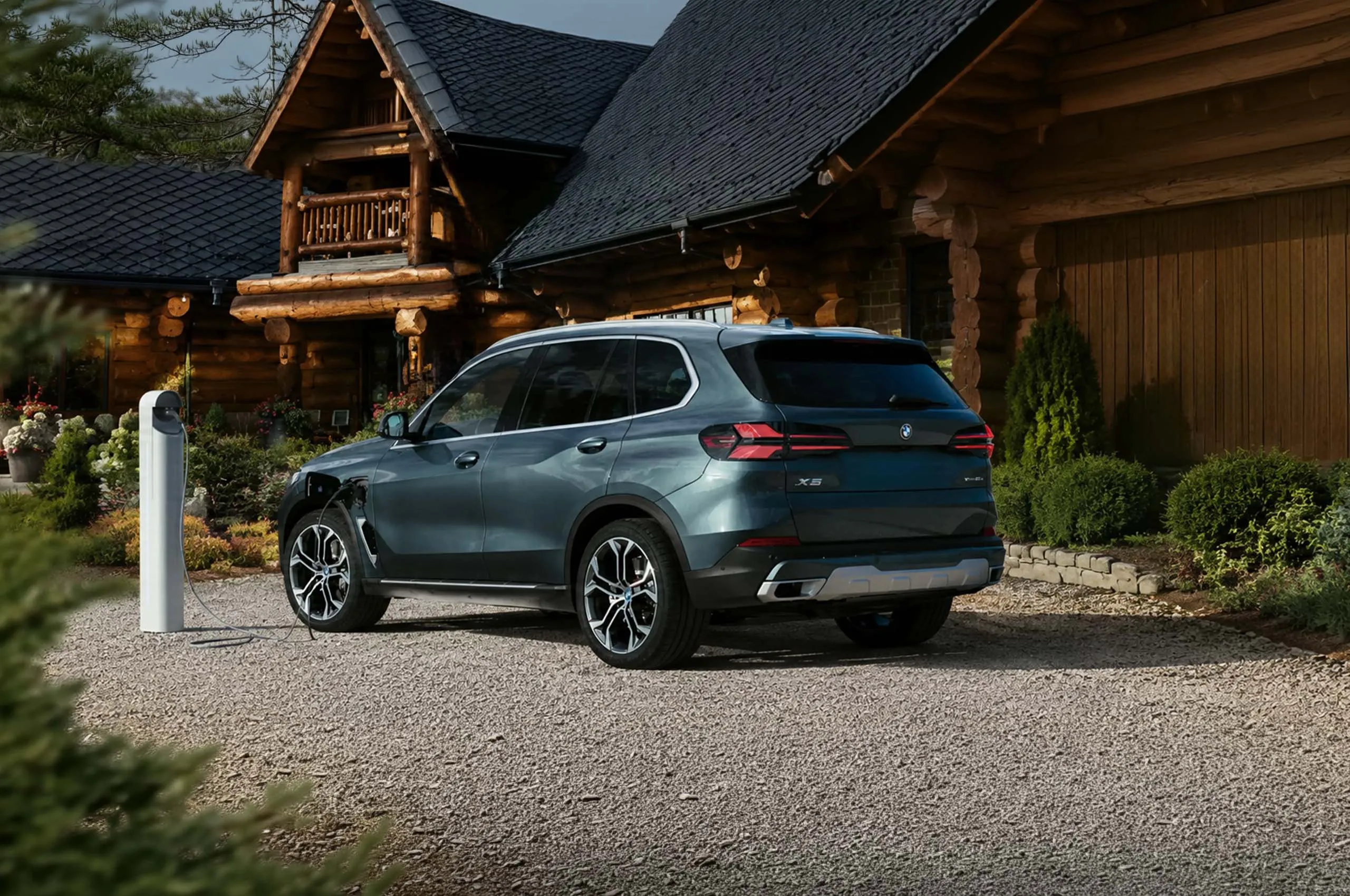 Un véhicule BMW chargeant devant une demeure rustique.